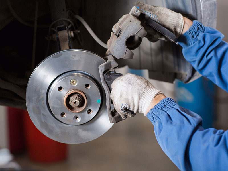 a man fixing a broken up engine  serviced by Brake Pros of Waltham in Billerica specializing in brake fluid change.