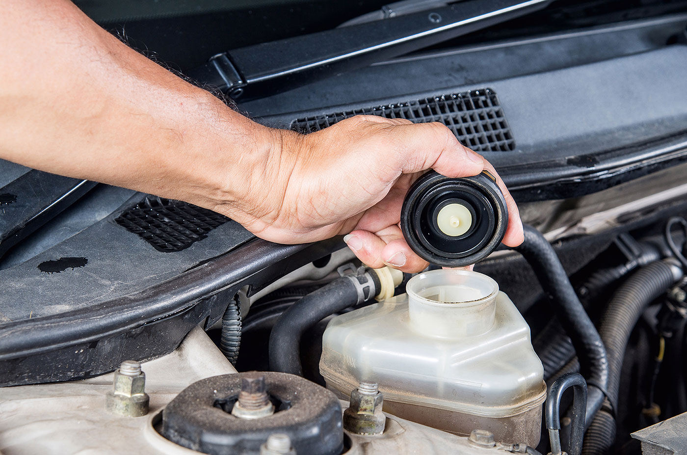 a person is using a small hose to clean a car  serviced by Brake Pros of Waltham in Waltham, MA specializing in brake repair Waltham.