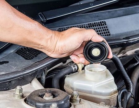 a person is using a small hose to clean a car  serviced by Brake Pros of Waltham in Waltham, MA specializing in brake repair Waltham.