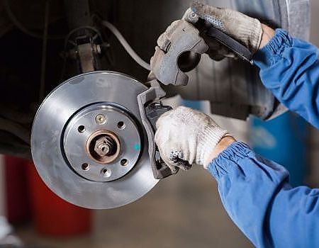 a man fixing a broken up engine  serviced by Brake Pros of Waltham in Belmont specializing in brake rotor servicing.